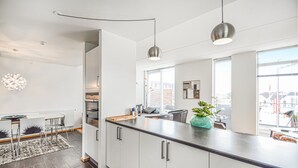 Een moderne keuken met een groot eiland, hangende lampen en uitzicht op de stad.