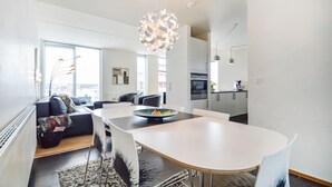 Een moderne woonkamer met een eetgedeelte, een keuken en een groot raam.