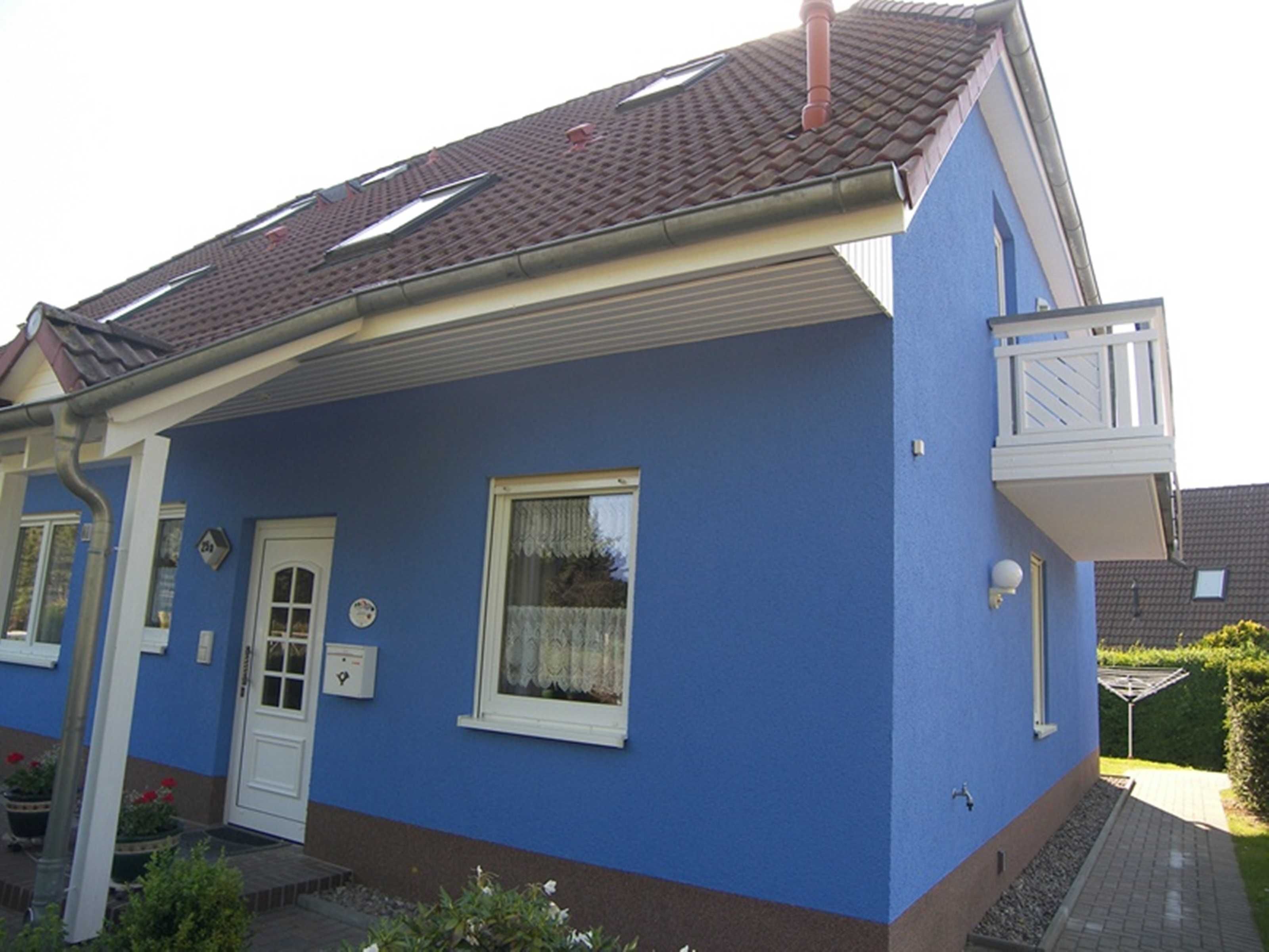 Et toetagers hus med blå facade, en hvid dør og en lille balkon på anden sal.