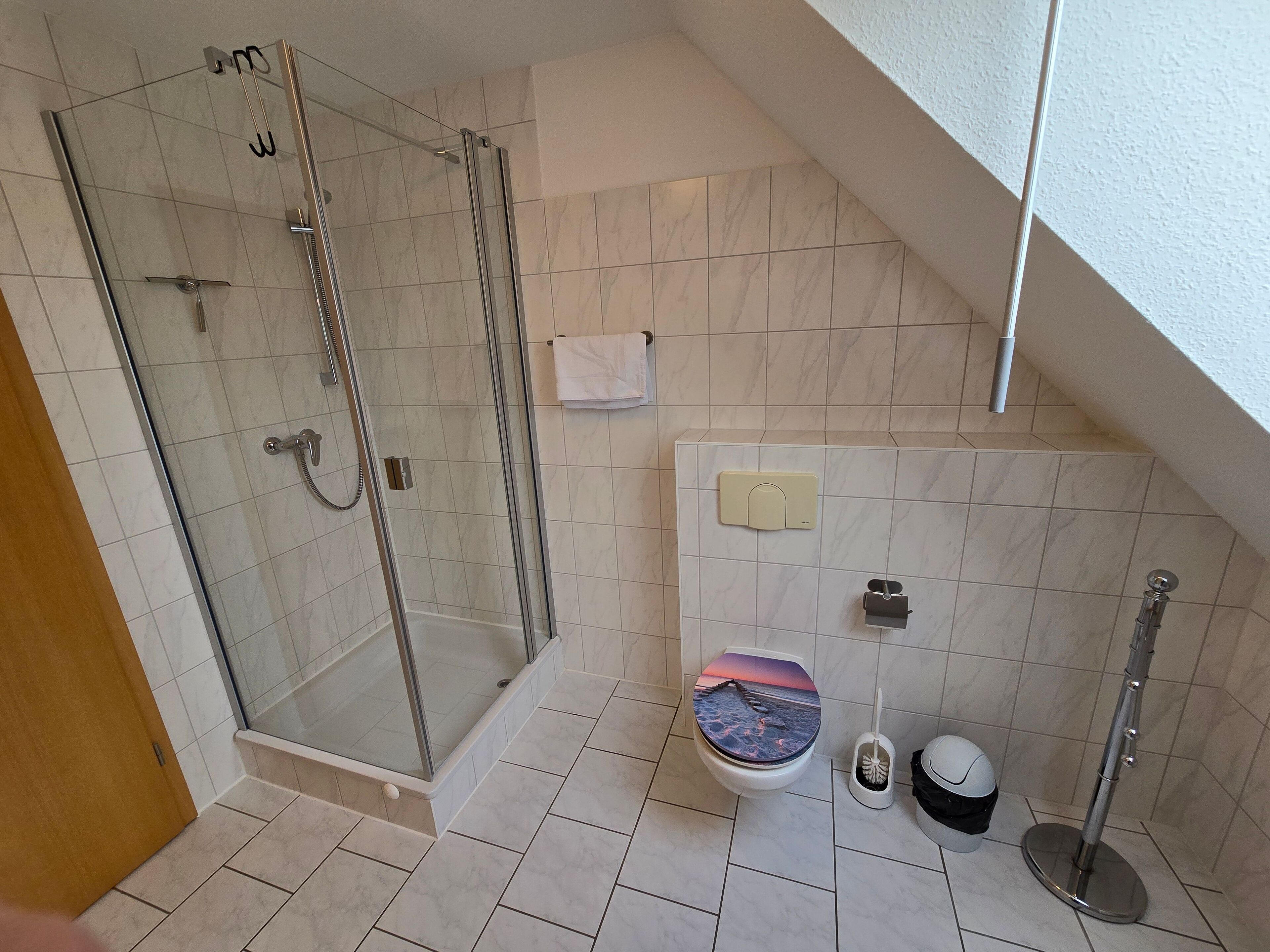 A modern bathroom with a glass-enclosed shower, a toilet with a decorative cover, and a bidet.