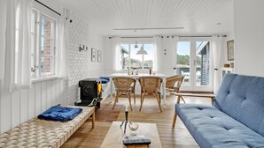Ein heller, offener Wohnbereich mit Kamin, Korbmöbeln und einem blauen Sofa.