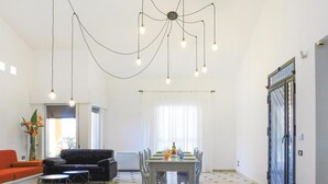 Un vaste espace de vie comprenant une table à manger pour quatre personnes, un canapé noir et une table basse aux motifs géométriques.