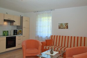 A compact living space with a kitchenette, a sofa, and a glass coffee table. - Beach chair house 5 150 m to the beach quiet residential area - Strandkorbhaus 5 150 m zum (Göhren)