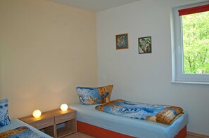 A bedroom with a bed, bedside tables, and a window with a view of trees. - Beach chair house 5 150 m to the beach quiet residential area - Strandkorbhaus 5 150 m zum (Göhren)