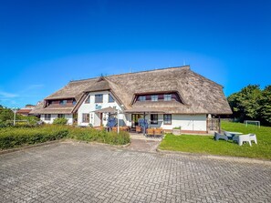 A traditional building with a thatched roof, a covered outdoor seating area, and a paved entrance.