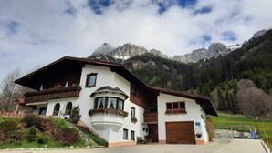 Un edificio de dos pisos con techo inclinado, un garaje amplio y vistas a las montañas.