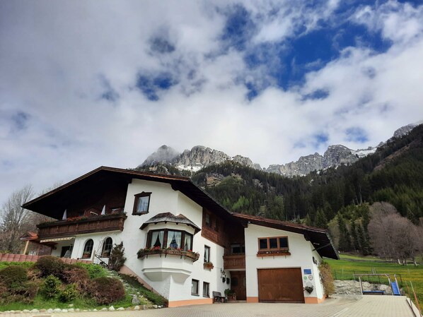 A two-story building with a sloped roof, a large garage, and a view of mountains.