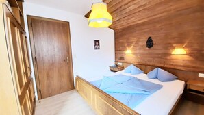 Una habitación con paneles de madera, una cama, una lámpara colgante y una lámpara de pared.