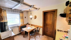 A compact kitchen with a dining table, chairs, a stove, and a radiator.