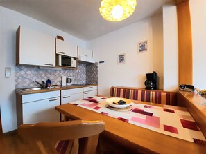 A compact kitchen with a microwave, sink, and a dining area with a table and chairs.