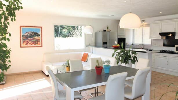 A modern kitchen with white cabinets, a dining table with four chairs, and a pendant light. - Beautiful home in Ancone (Ancone)