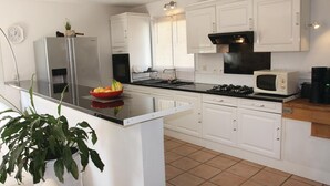 A modern kitchen with white cabinets, a stainless steel refrigerator, a microwave, and a gas stove. - Beautiful home in Ancone (Ancone)