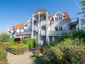 A multi-story residential building with balconies, a covered walkway, and a garden area.