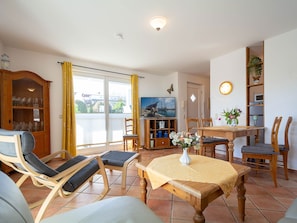 A living room with a dining area, a television, and a view of the outdoors.