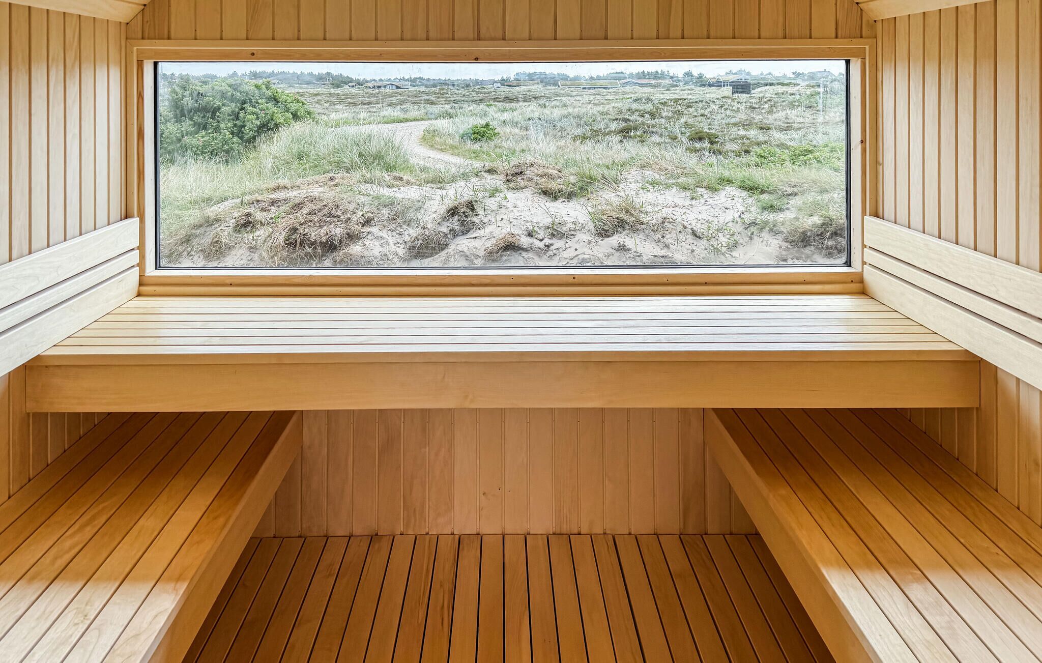 Un sauna doté d’une grande fenêtre donnant sur un paysage verdoyant.