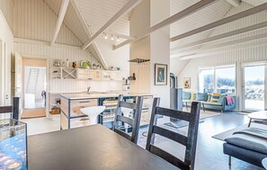 Un'ampia cucina con isola centrale, zona pranzo con sedie, divano e una grande finestra vista.