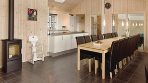 Una cocina moderna con armarios blancos, una isla central y un comedor con una mesa larga y sillas.