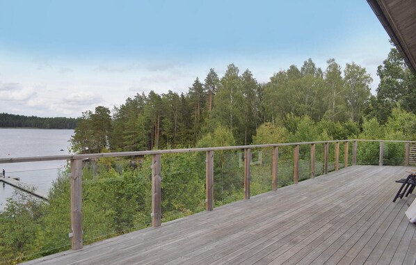 A wooden deck with a railing overlooking a lake and forest.