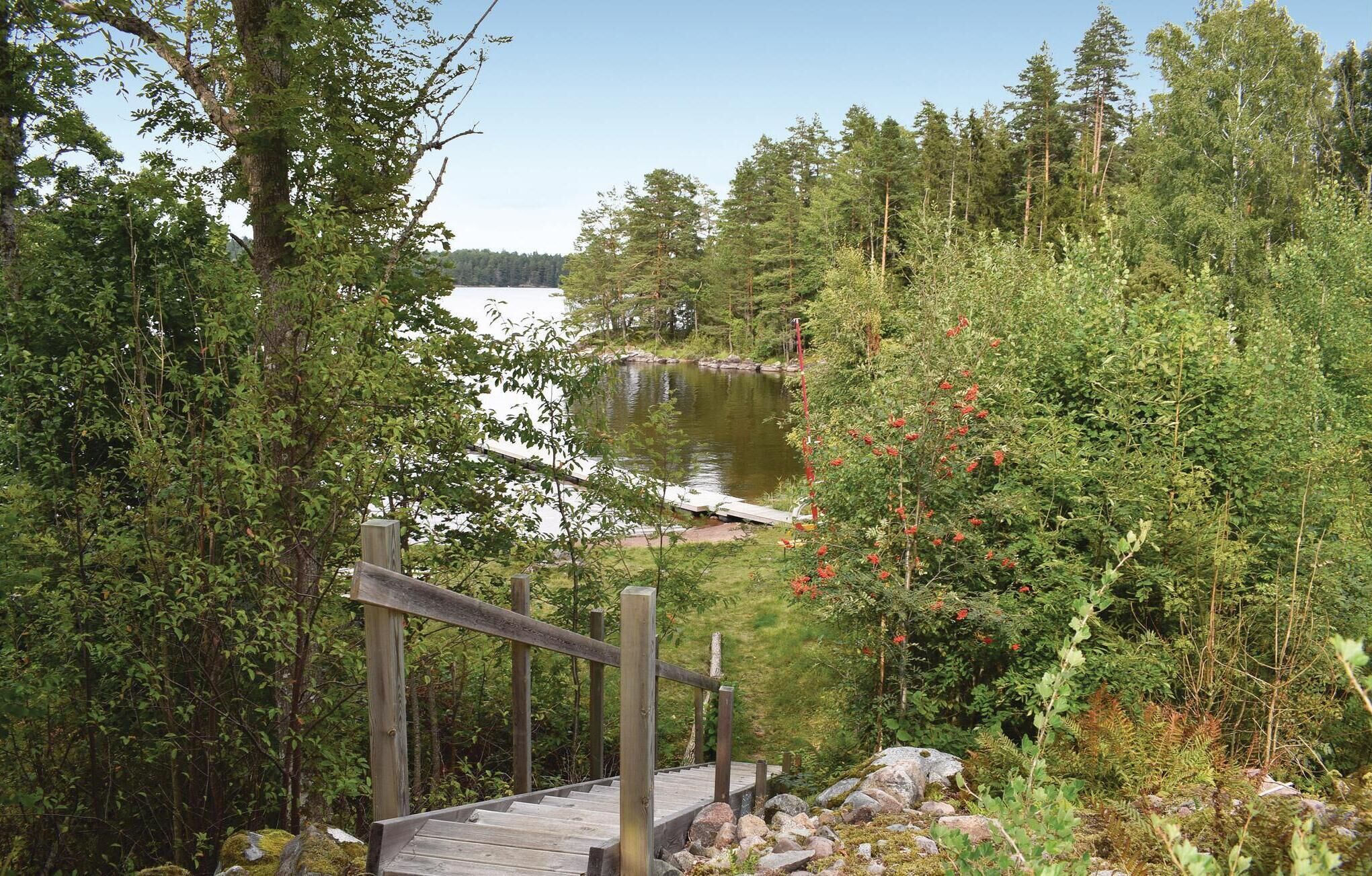 A wooden deck leading to a lake surrounded by dense forest.