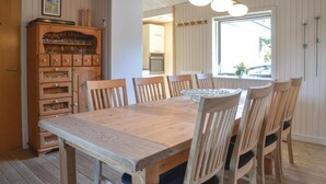 Un comedor con una mesa y sillas de madera, un aparador con cristalería y una ventana con vistas.