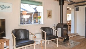 Una sala de estar acogedora con dos sillones de cuero, una mesita, una chimenea y una ventana decorada.