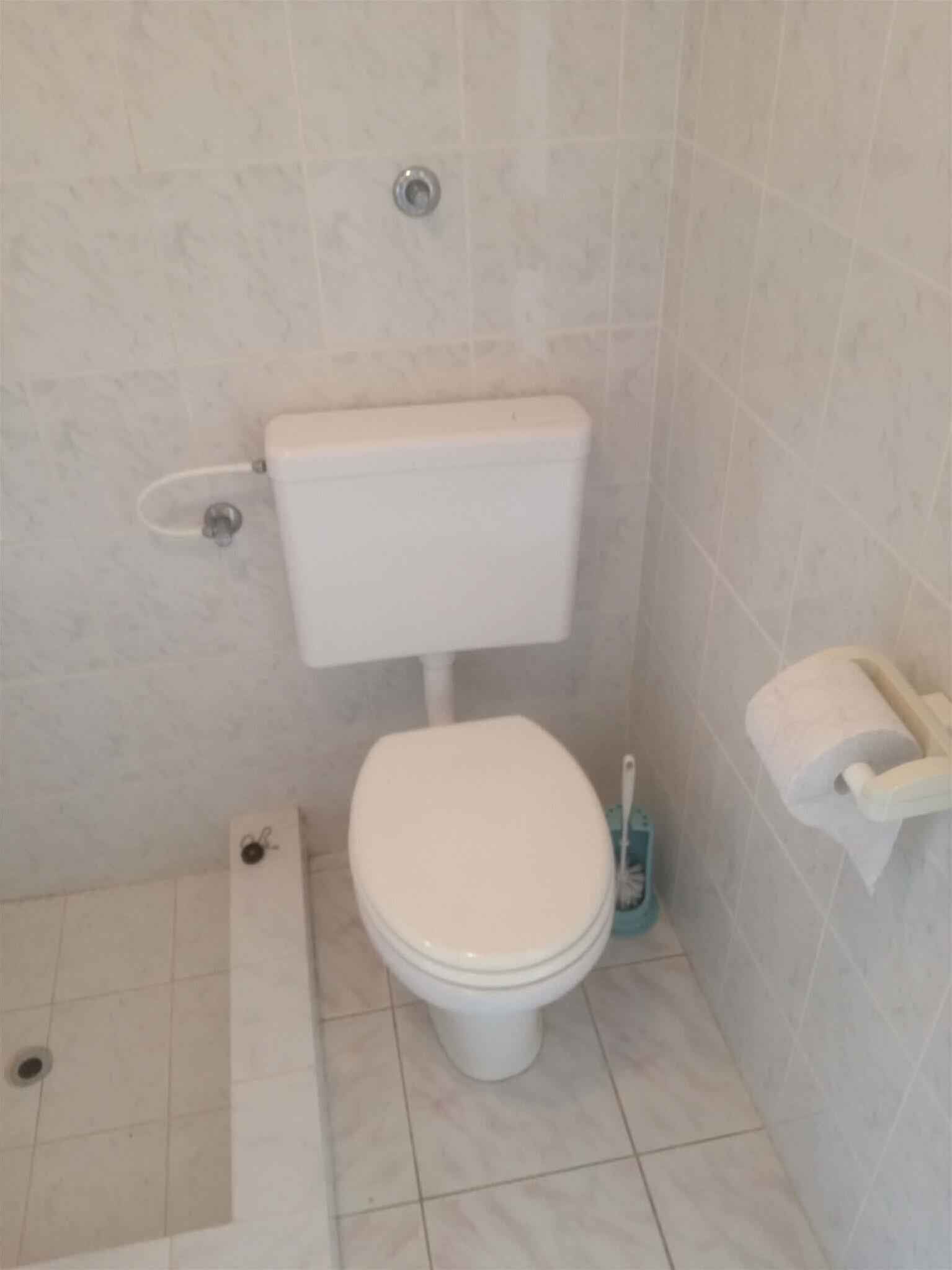 Une petite salle de bain comprenant des toilettes, un bidet et un porte-rouleau de papier toilette.