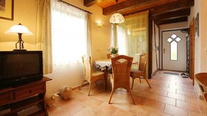 A cozy living room with a television, wicker chairs, a dining table, and a wooden ceiling. - Apartment 1 - Fewos "Storchenhof" near the lake (Meesiger)