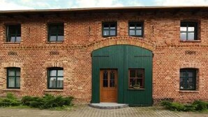 A brick building with a green arched entrance and a wooden door. - Apartment 1 - Fewos "Storchenhof" near the lake (Meesiger)