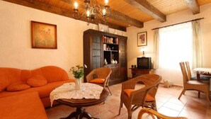 A cozy living room with a wooden ceiling, a sofa, wicker chairs, a table with a vase, and a bookshelf. - Apartment 1 - Fewos "Storchenhof" near the lake (Meesiger)