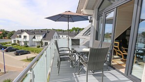 Ein Balkon mit Korbmöbeln, einem Tisch und einem Sonnenschirm.