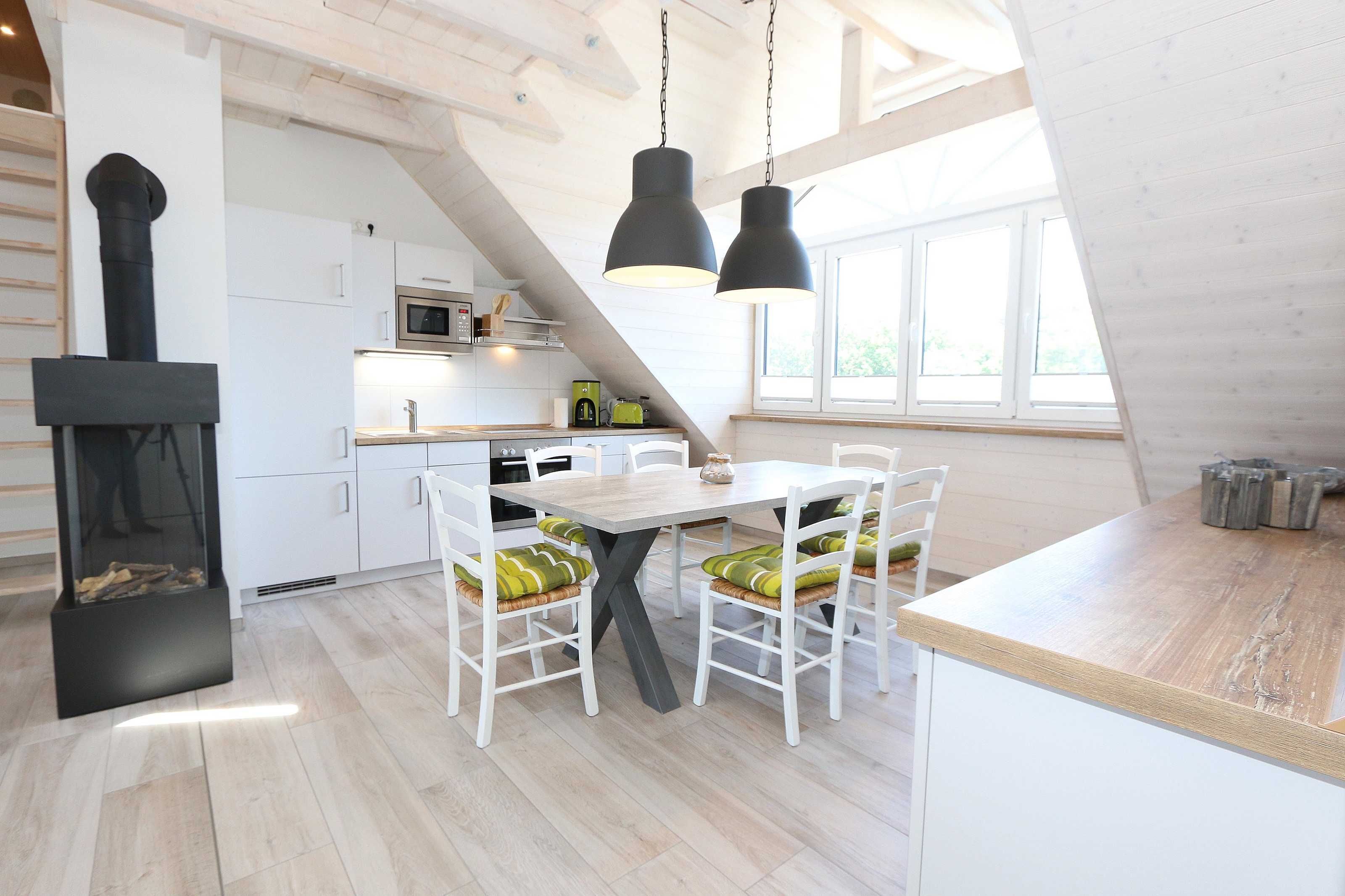 Une cuisine moderne avec des meubles blancs, une table à manger en bois et un fourneau noir.