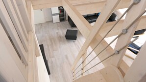 Ein modernes Interieur mit einer Holztreppe, einer schwarzen Sitzbank und einem weißen Schrank im Hintergrund.