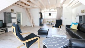 Ein großzügiges Loft mit hohen Decken, freiliegenden Holzbalken, einer Küchenzeile, einem Essbereich und einem Wohnbereich mit modernen Möbeln.