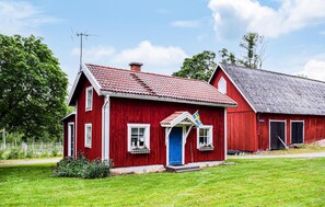 Une maison en bois rouge avec une porte bleue, des fenêtres blanches et un petit porche agrémenté de jardinières.