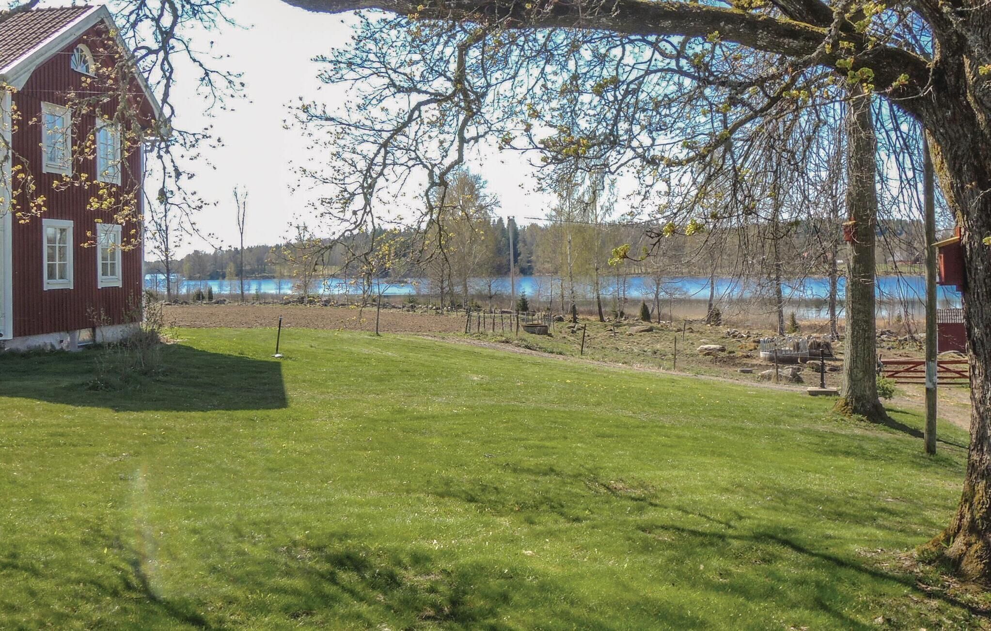 Punainen talo, jossa on nurmikko ja näkymä järvelle.