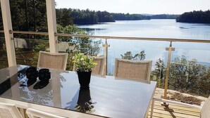 A glass table with chairs on a balcony overlooking a lake. - Gorgeous home in årjäng with WiFi (Årjäng)
