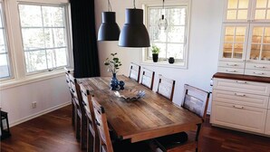 A dining room with a wooden table, chairs, pendant lights, and a window with a view of trees. - Gorgeous home in årjäng with WiFi (Årjäng)