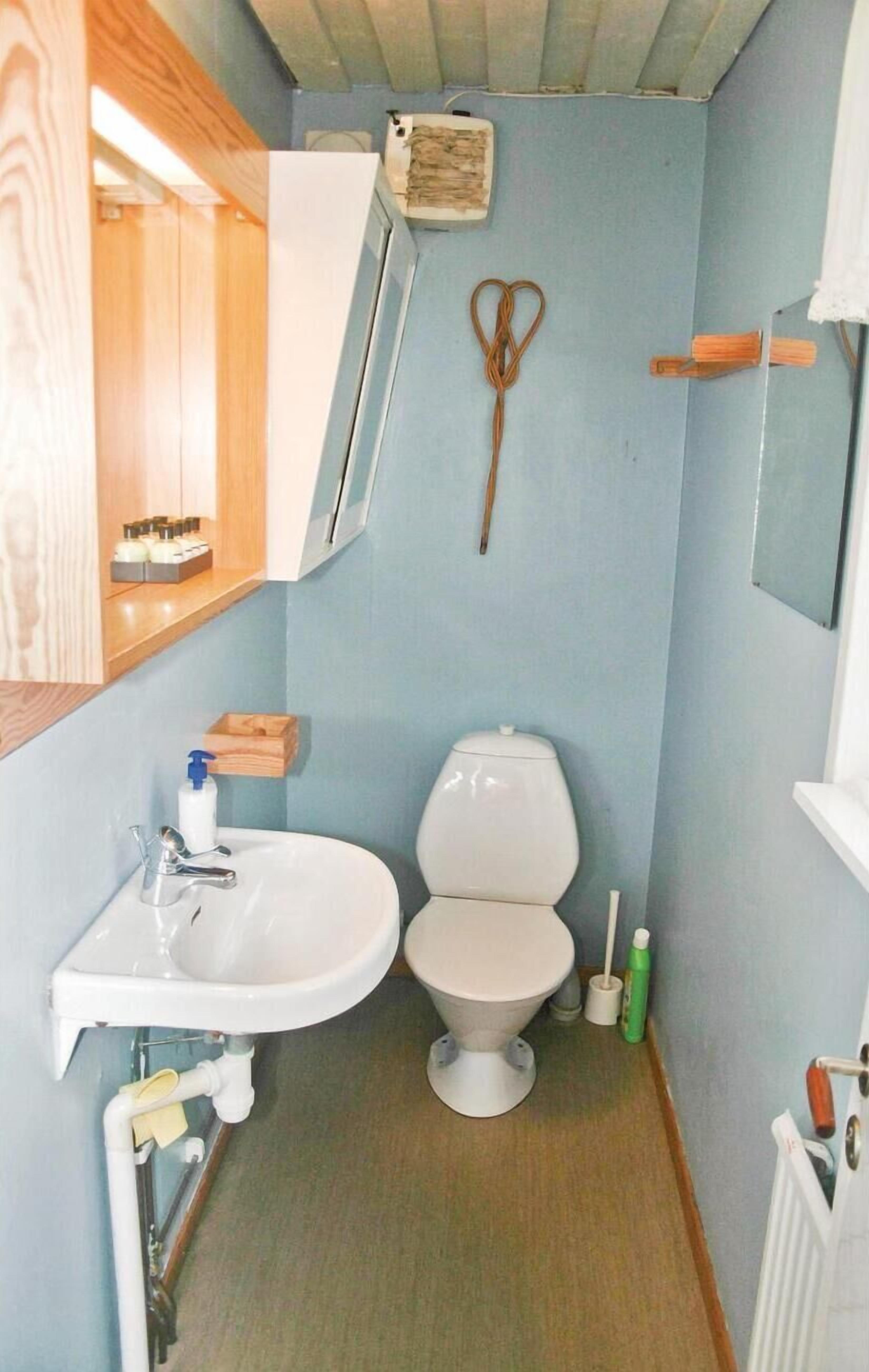 Un baño pequeño con un lavamanos blanco, inodoro y un mueble de madera sobre el lavamanos.