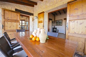 A wooden dining table with a pitcher and oranges, surrounded by wicker chairs. - 44252 Finca Son Homar (license number ET / 3279) - 44252 Finca Son Homar (Petra)