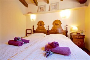 Une chambre d’hôtel avec un lit double, deux tables de chevet, une tête de lit en bois et un luminaire fixé au mur.