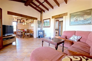 A cozy living room with a sofa, a television, a fireplace, and a dining area with chairs and a table.