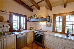 A kitchen with a stove, oven, and a window with a view of greenery. - 44252 Finca Son Homar (license number ET / 3279) - 44252 Finca Son Homar (Petra)