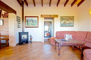A living room with a sofa, a table, a fireplace, and artwork on the walls. - 44252 Finca Son Homar (license number ET / 3279) - 44252 Finca Son Homar (Petra)