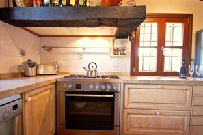 A kitchen with a Bosch gas stove, an oven, wooden cabinets, and a hanging shelf above the stove. - 44252 Finca Son Homar (license number ET / 3279) - 44252 Finca Son Homar (Petra)