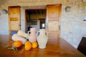 A rustic interior with stone walls, wooden doors, and a table with pottery and oranges. - 44252 Finca Son Homar (license number ET / 3279) - 44252 Finca Son Homar (Petra)