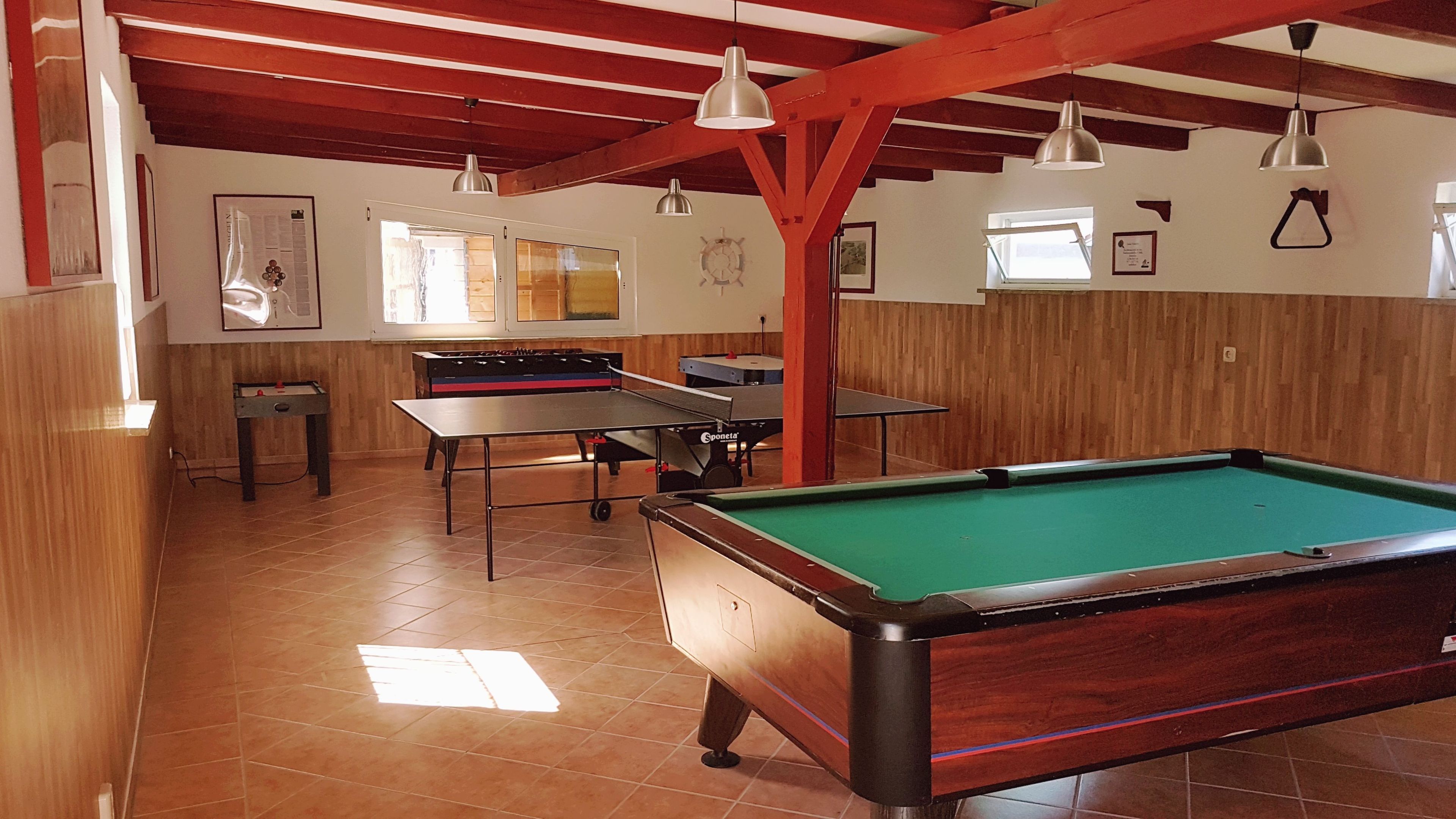 A recreational room with a pool table, foosball table, and ping pong table.