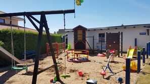 Ein Spielplatz mit Schaukeln, Rutschen, Klettergerüsten und einem Sandkasten.