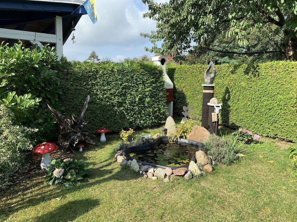 Ein Garten mit Teich, Felsen und einer Statue.