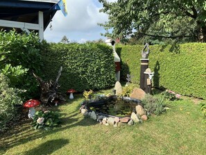 Ein Garten mit Teich, Felsen und einer Statue.