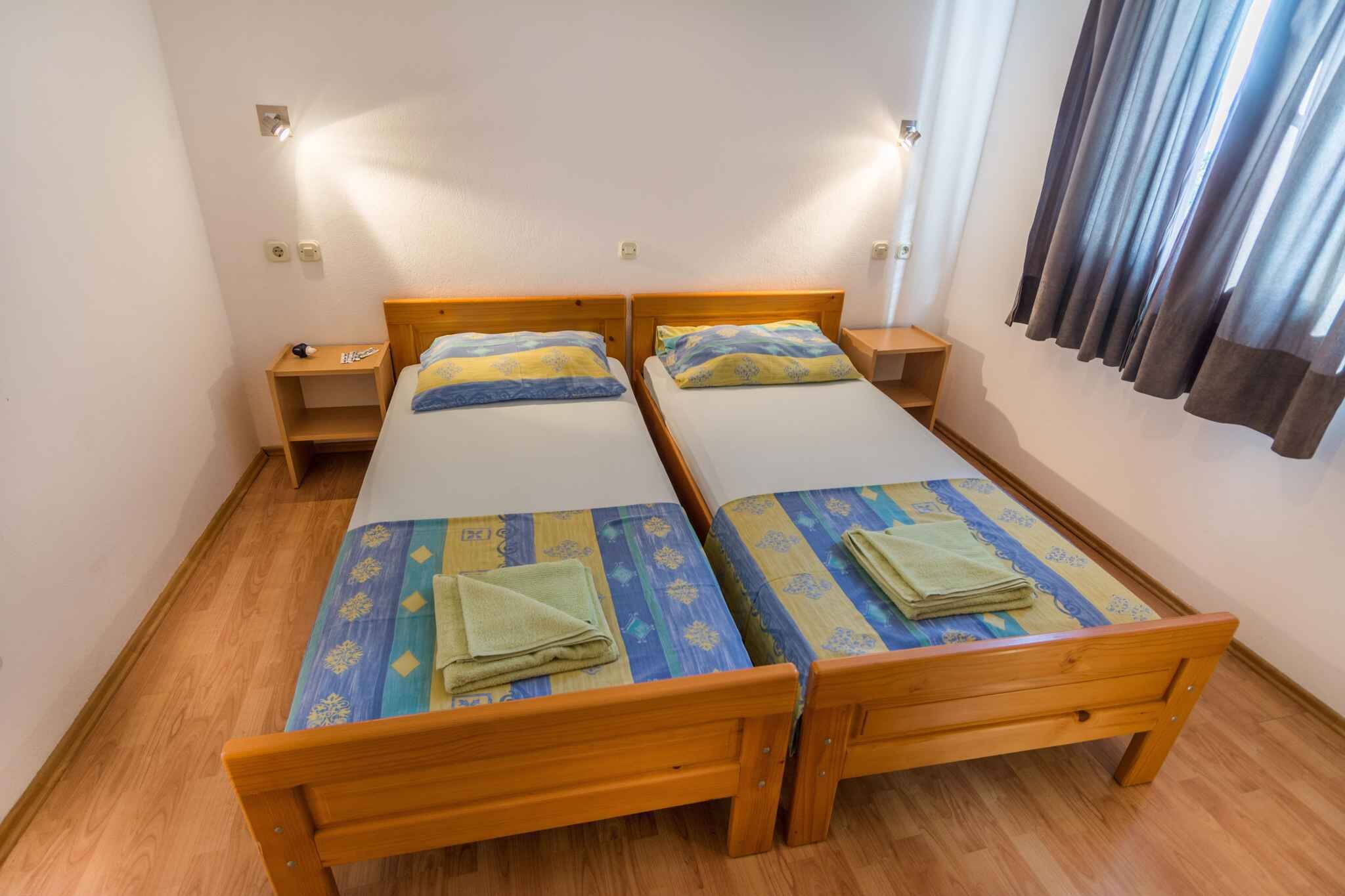 A room with two wooden beds, each with a matching nightstand. The beds have patterned bedding and folded towels.